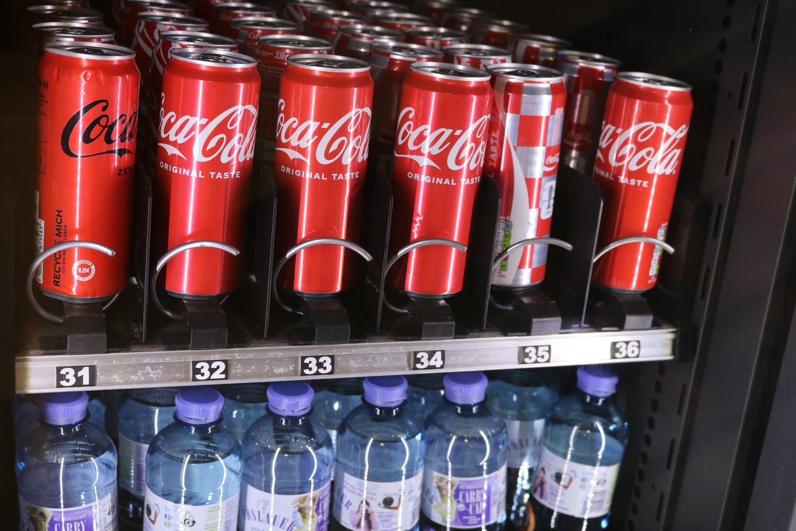 Voll bestückter Getränkeautomat mit Cola-Dosen und Wasserflaschen